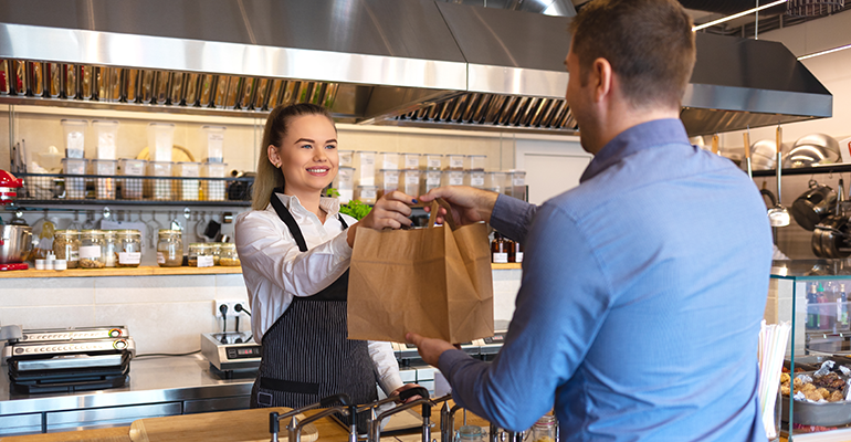 Happy-waitress-waring-apron-serving-customer-at-counter-in-small-family-eatery-restaurant.-Small-business-and-entrepreneur-concept-with-woman-owner-in-eatery-with-takeaway-service-delivery-1127824238_5800x3866-(2).png