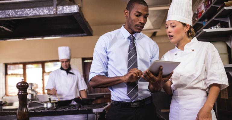 Male manager and female chef using digital tablet in kitchen.jpg