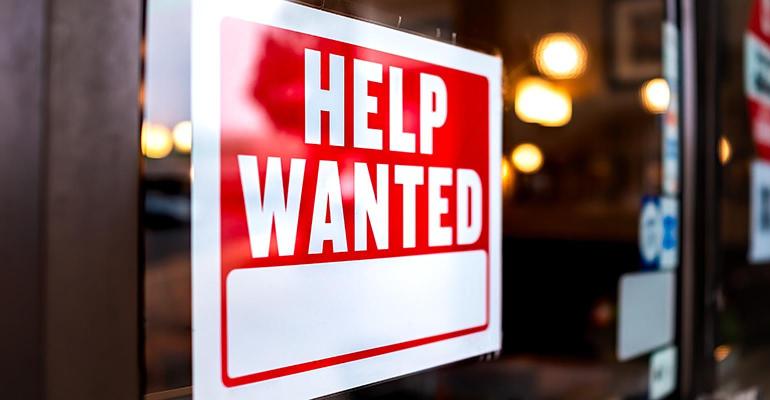 Red help wanted sign posted in a window