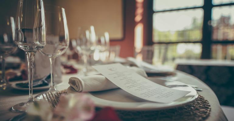 A restaurant table with wine glasses and a menu at the table setting