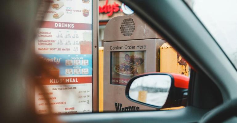 A person orders through their car window at a drive-through