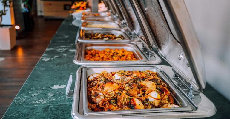 A line of catering trays on a green tablecloth