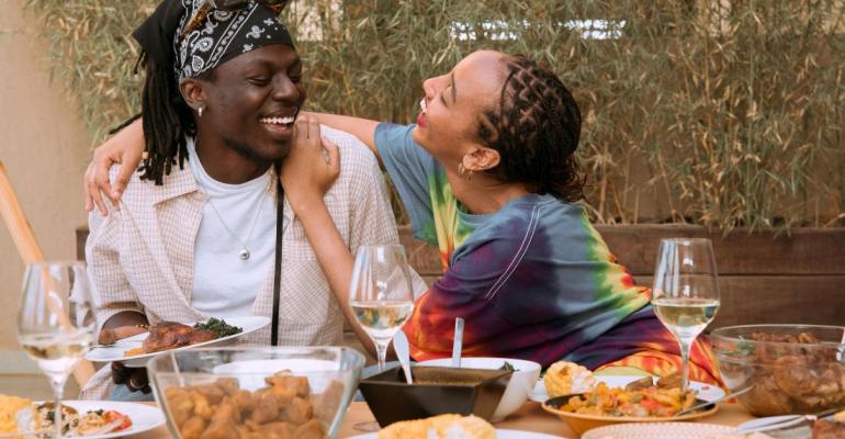 Two Gen Z laughing over plates of food