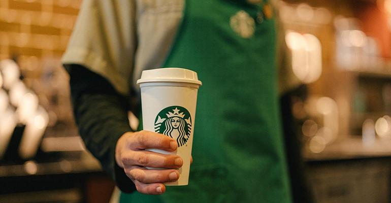 A Starbucks barista holding a cup