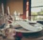 A restaurant table with wine glasses and a menu at the table setting