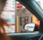 A person orders through their car window at a drive-through