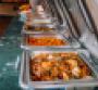 A line of catering trays on a green tablecloth