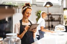 Restaurant worker smiling while holding tablet