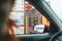 A person orders through their car window at a drive-through